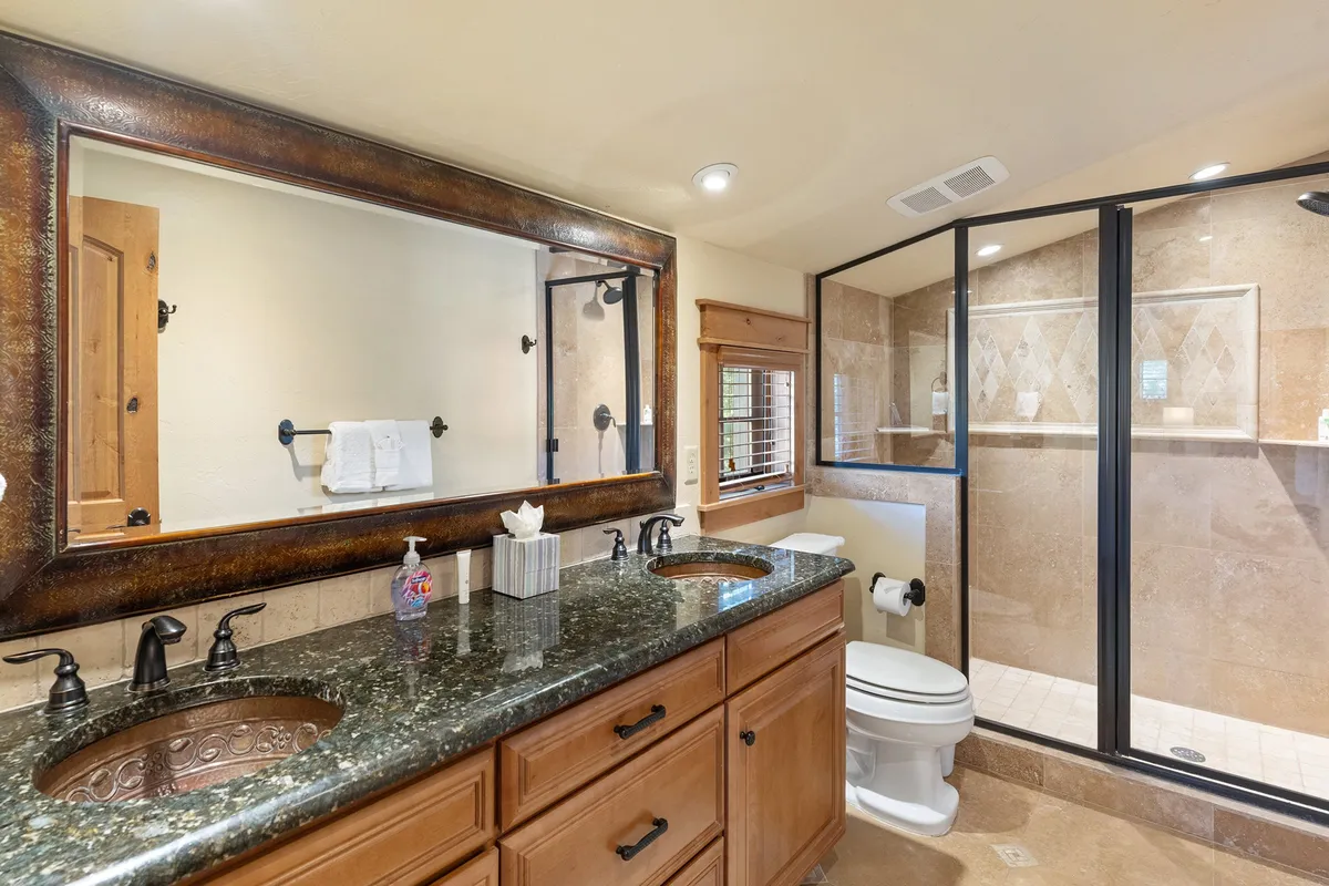 A modern, well-lit bathroom with a double sink vanity, expansive mirror, and glass shower enclosure. The clean lines and contemporary finishes create a spa-like atmosphere, ideal for unwinding and refreshing after a day of activity.