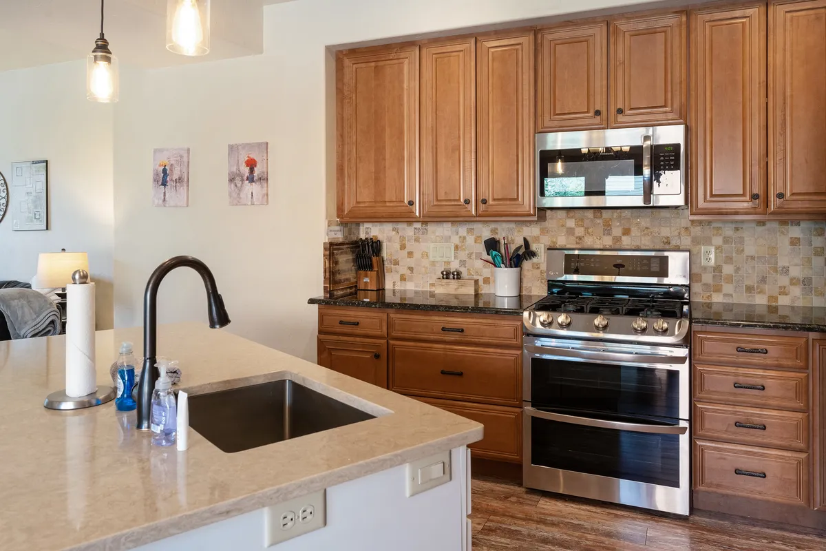 A welcoming kitchen scene featuring a central island with bar stools, sleek stainless steel appliances, and custom cabinetry. The space feels open and ideal for cooking or gathering, with plenty of counter space for preparing meals after a day on the slopes.