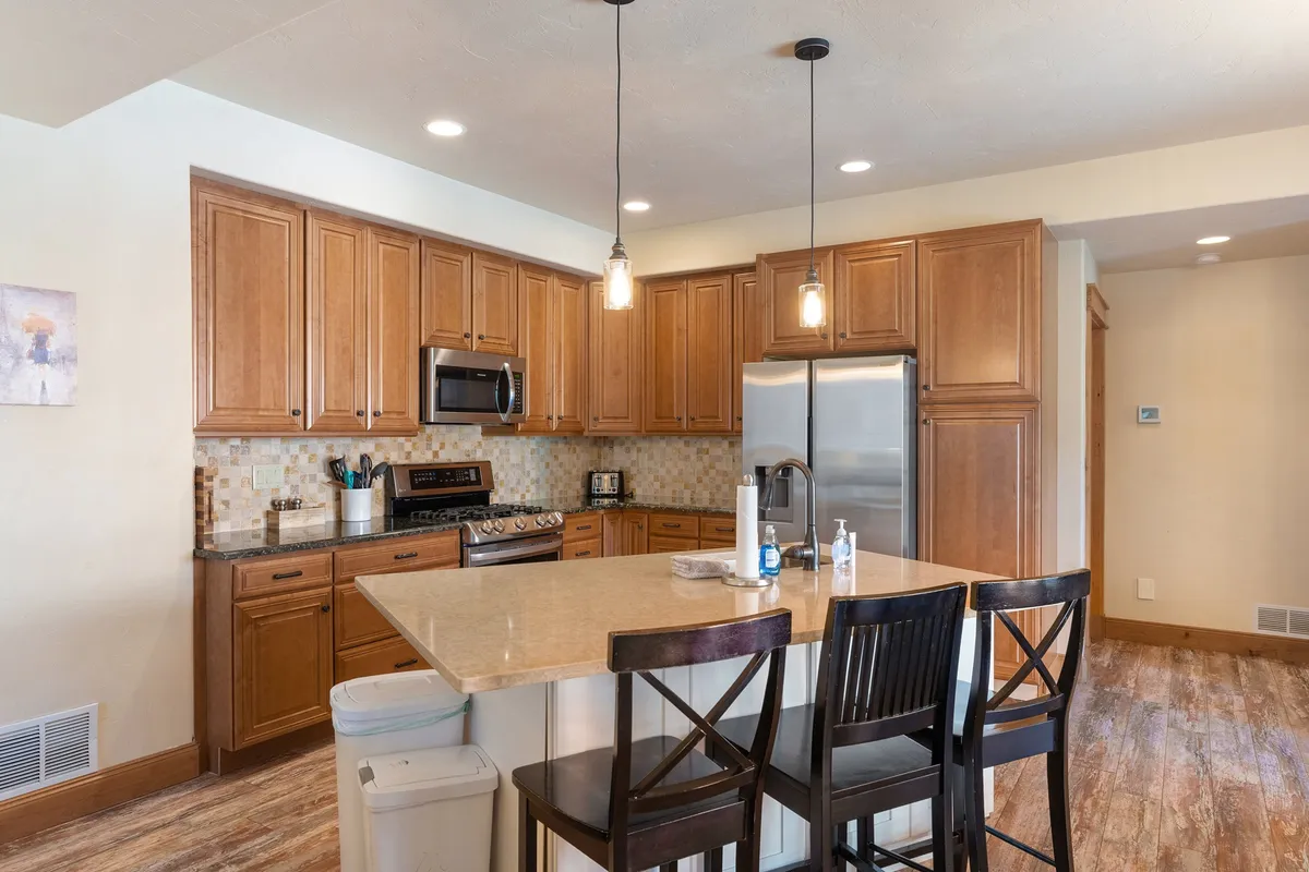 A welcoming kitchen with a large island, wood cabinetry, and stainless steel appliances. The space feels open and social, ideal for gathering after a day on the slopes or trails. It radiates comfort and adaptability for both relaxing summer meals and wintertime gatherings.
