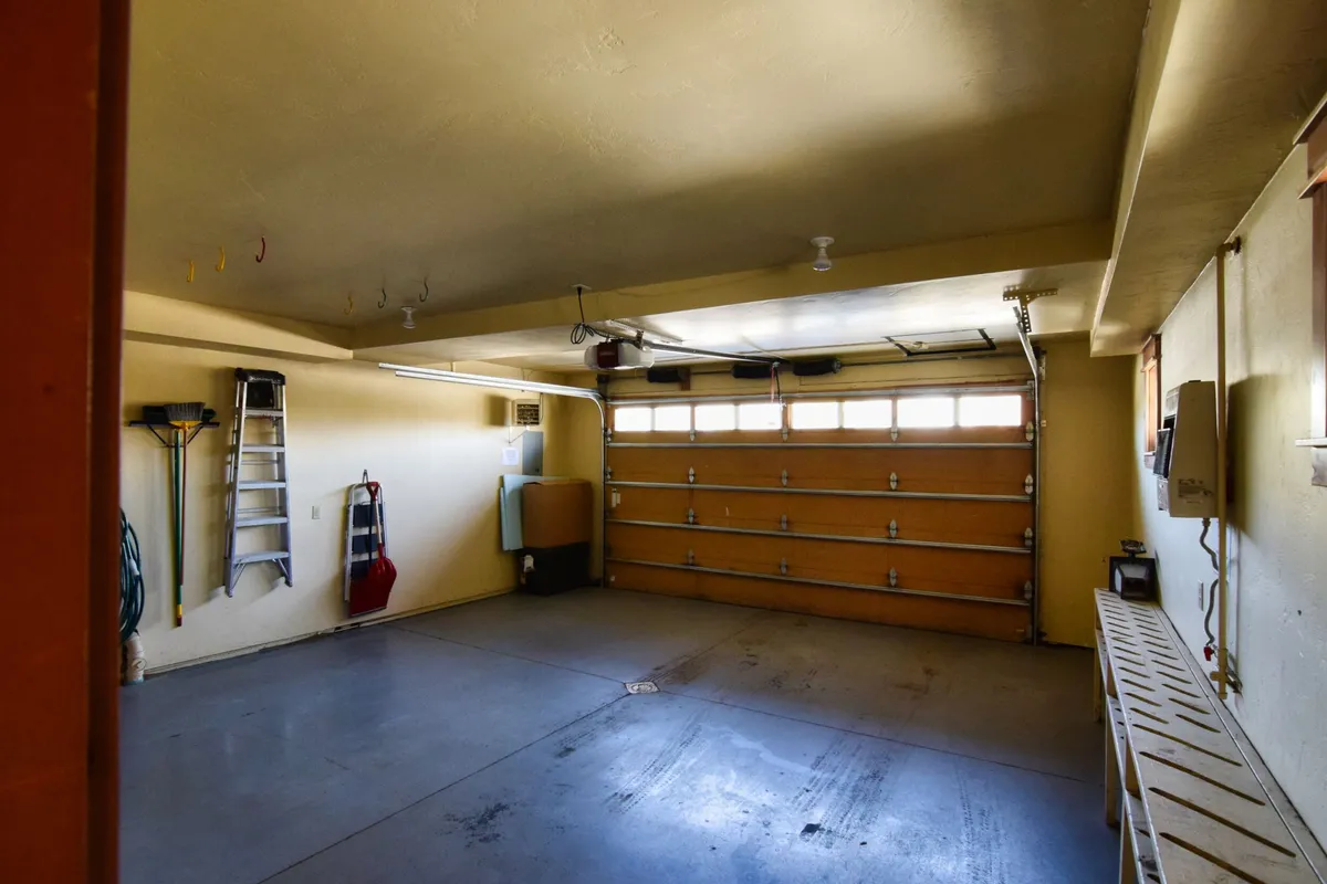 This image features a clean and practical garage area, with a prominent garage door, workbench, ladder, and storage hooks along the wall. It highlights the space available for vehicle parking and storing outdoor gear, aligning with the section's emphasis on convenience and flexibility.