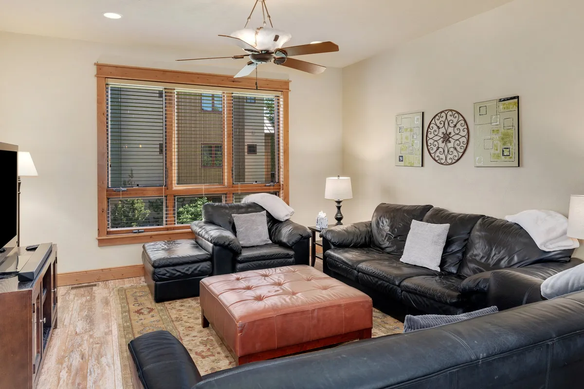 A welcoming living room with leather sofas and a coffee table, bathed in warm light from a window. The space invites relaxation, conversation, or movie nights after a day spent outdoors.