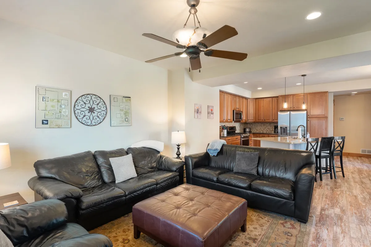 A cozy living room furnished with black leather sofas, decorative wall art, and a central coffee table. The space feels inviting and comfortable, ideal for movie nights, casual gatherings, or relaxing with a book after a day outdoors.